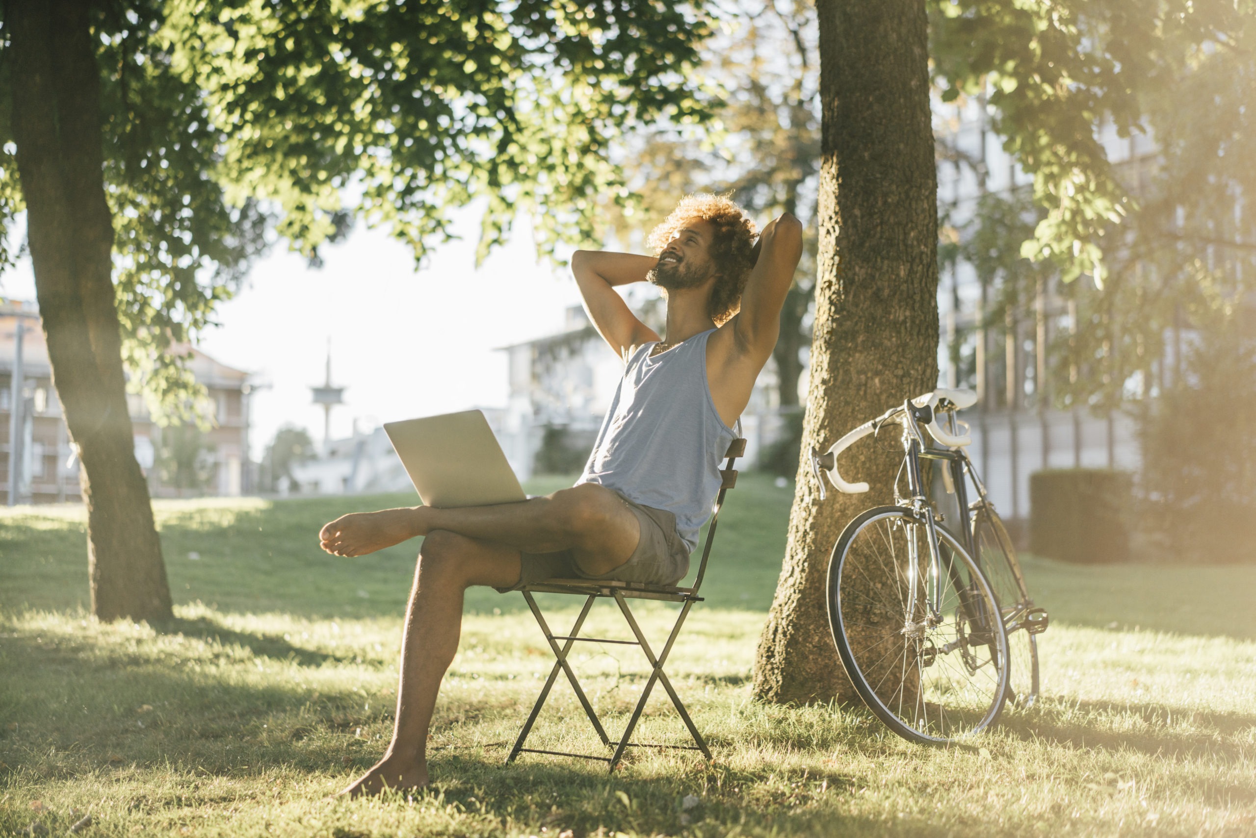 Man with beard and curly hair using laptop in park
